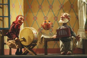 Granny with the drums and Granddad with the lajna instrument, joined by <i>Speckles the Ball</i> who has flown in through the window. The puppets were fabricated by Jan Malik, the performance saw its première at the City Puppet Theatre (today's <!--LINK'" 0:724-->) in 1951 and became immensely popular around Slovenia.