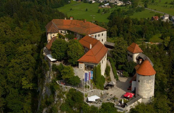 Aerial view of Bled Castle showing the layout of castle buildings around the upper and lower courtyards, connected with a staircase. The oldest part of the castle is the Romanesque entrance tower, other sections are Gothic and Renaissance styles.